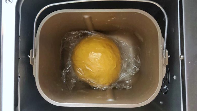 南瓜豆沙排包,6、拨掉面包机的插头,盖好保鲜膜盖上盖子于面包机中直接室温发酵。