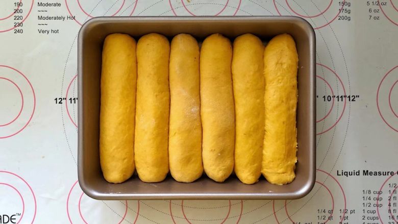 南瓜豆沙排包,14、收口向下码入学厨9寸烤盘中,盖上保鲜膜进行二次发酵。