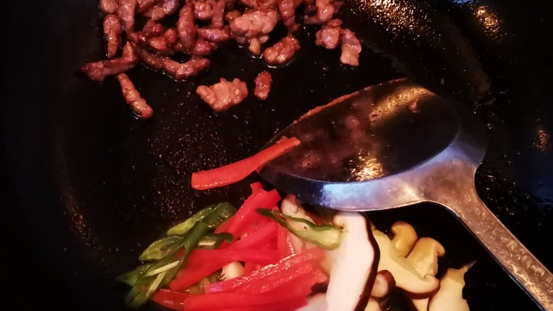 牛肉虾仁炒米线,将炒熟的牛肉到锅的一边,放入青红椒和香菇翻炒