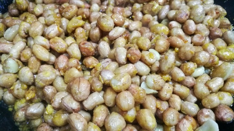 满满童年记忆的糖霜花生,快速把所有烤过的花生米倒入糖浆里,用铲子不停地翻炒,尽量让所有花生米都裹上糖浆,火力保持在中小火。糖浆里的水分慢慢被炒干,就会开始反沙,一旦出现白霜,就把火给关掉。