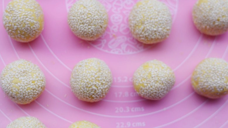 烤箱低油版奶香烤南瓜芝麻饼,每一个圆球表面裹上白芝麻,将芝麻往里按一按。