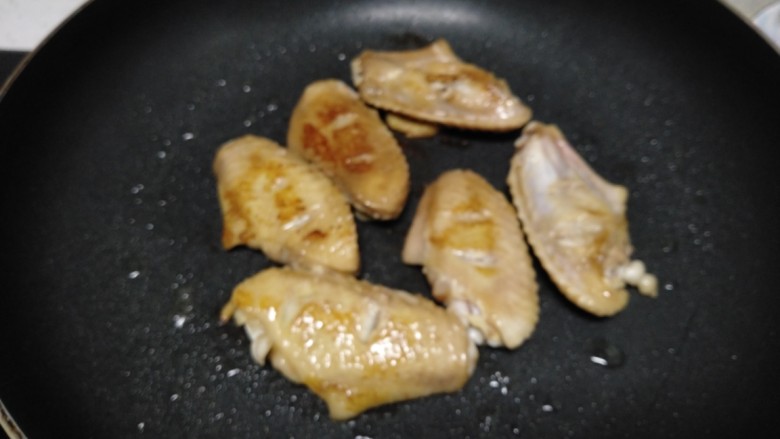 可乐鸡翅,不粘锅中放入适量油，放入鸡翅煎至两面金黄。