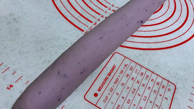 紫薯馒头，柔软超弹,在案板上搓成长条状。