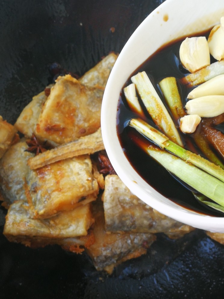 红烧带鱼#年年有余#,倒入调好的料汁。晃动均匀,让料汁均匀的裹在带鱼上