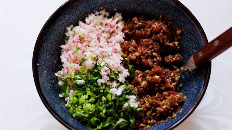 长长久久的翡翠白玉牛肉萝卜饺子,把水萝卜和香菜末倒入搅拌好的牛肉馅里。