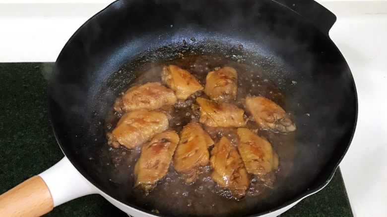 蜜汁鸡翅,盖上锅盖,中火焖炖15分钟,炖好后,开大火收汁,完全收干,让酱汁在鸡翅上挂住。