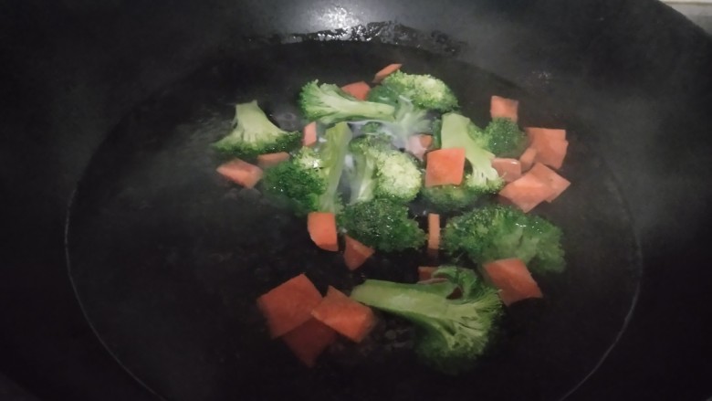 西兰花炒平菇,锅中放入适量清水,水开后放入西兰花焯水60秒,放入胡萝卜焯水30秒,放入平菇焯水30秒。