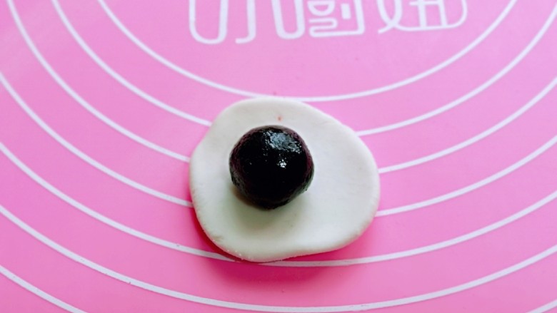 预热元宵节~猪圆玉润芝麻汤圆,取一块小面团揉圆,用擀面杖擀圆,放上<a style='color:red;display:inline-block;' href='/shicai/ 668'>黑芝麻</a>馅,虎口手法包起来,收口捏紧再揉圆。