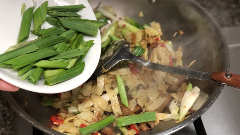 #猪年#舌尖上的家乡味➕腊肉蒜苗炒豆丝,继续翻炒一分钟,然后加入蒜叶,中大火翻炒均匀