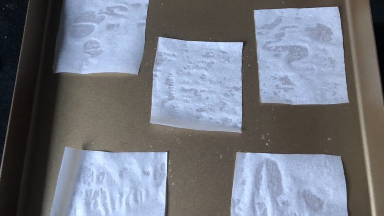 葡萄干肉桂胚芽贝果,剪10厘米见方的五片油纸,反面略打湿后,贴在烤盘上。