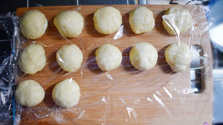 奶香葡萄干小面包(电饭锅版),分成12个大小的面剂子,并用保鲜膜盖住,备用。