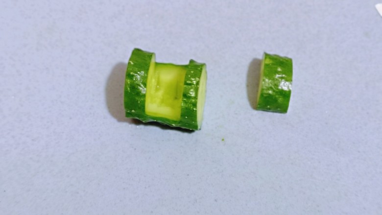 迎新春美好寓意~翠竹报春,之后开始做黄瓜盅,在黄瓜的两边切出约1厘米左右深度的薄片,再一段黄瓜的两边,轻轻的划开,不要切到底部,之后再沿着此开口横切,将上面这块黄瓜拿掉。