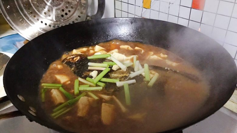 豆瓣酱千岛湖鱼头豆腐,时间到,加入青蒜的尾部白色部分,转大火,再煮2.3分钟