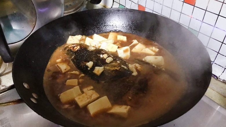 豆瓣酱千岛湖鱼头豆腐,15分钟后,把鱼头翻个身,再加入豆腐,然后盖上锅盖继续煮15-20分钟