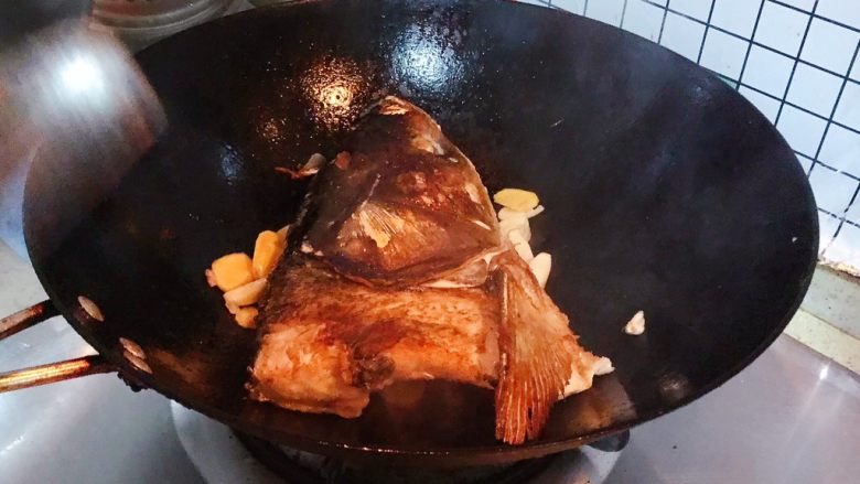 豆瓣酱千岛湖鱼头豆腐,加入生姜和大蒜,煎至鱼头两面金黄