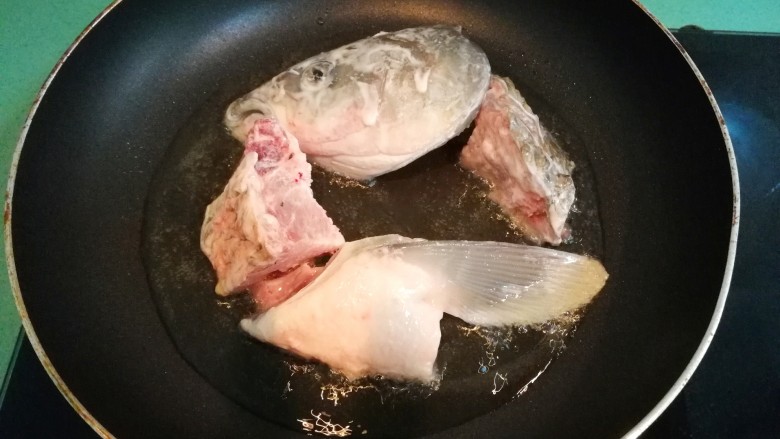 砂锅鱼头豆腐煲,油温八成热时,放入裹了生粉的鱼头块