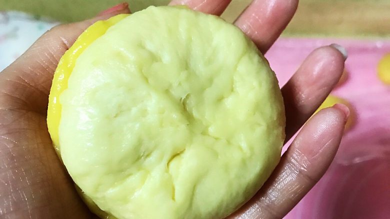 港式菠萝油面包,手掌把酥皮包裹到一个小面团上,用手慢慢按压面团中间收口位置,使整个酥皮包裹到面团3分12,然后收口朝下摆放
