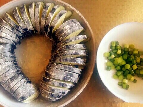 肉末盘龙茄,茄子放入盘中,撒上适量面粉,蒜苔切小粒。