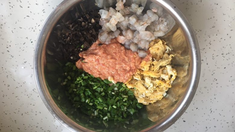 #猪五花肉# 猪肉韭菜虾仁水饺,将所有食材放在一起。 先在韭菜上洒上1勺(约15g)的香油,用香油把韭菜拌一拌,香油裹住韭菜,以保留韭菜的水分。