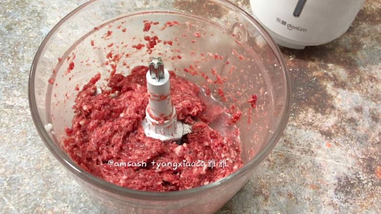 自制牛肉丸,先将水预留10克左右,然后将所剩的水分三次把冰水加入牛肉中
