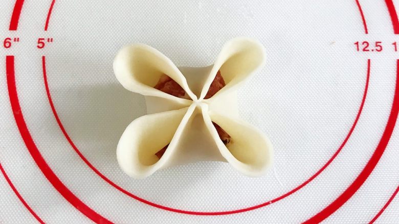 四喜蒸饺,先给饺子皮对角刷点水,筷子对角夹紧,再把每一个花瓣边缘捏薄些。