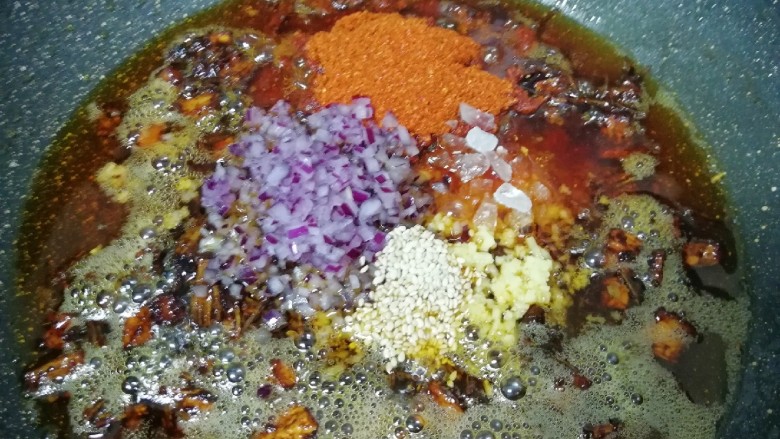 菌菇素辣酱,放入白芝麻、辣椒粉、冰糖碎、洋葱碎末和生姜碎末,转小火炒至辣椒出红油。