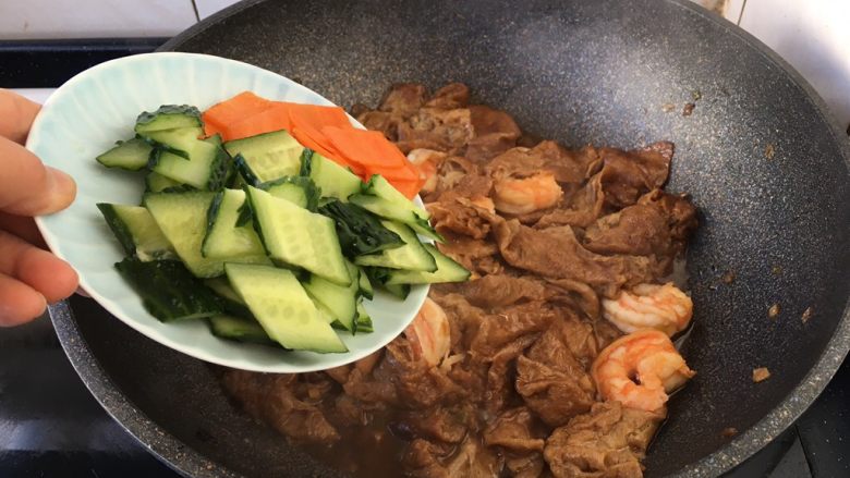 虾仁笃面筋(天津菜),放入黄瓜片和胡萝卜片且翻炒均匀。