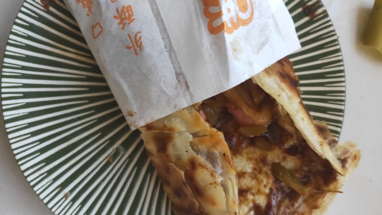 街头手抓饼的吃法----懒人必备早餐,卷起来放入纸袋中,懒人早餐就做好了。