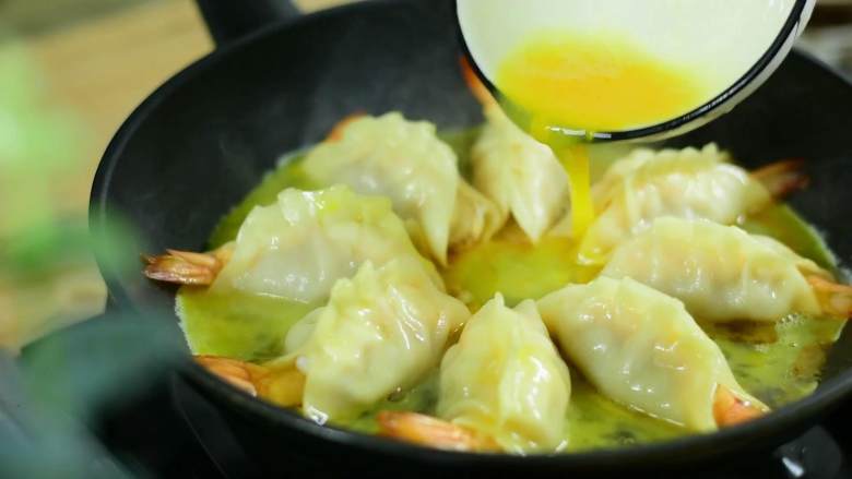 光是看着都流口水的大虾抱蛋煎饺,倒入蛋液,小火煎至蛋液凝固。