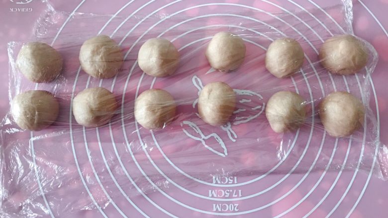 猪猪椰蓉小面包,面团排气后平均分成31克的12个小面团,覆盖保鲜膜松弛15分钟。