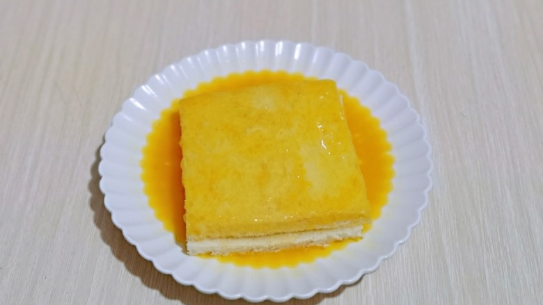 快手早餐~香蕉酸奶三明治,放入打散的蛋液盘中,将吐司的两面及四边均匀裹上蛋液。