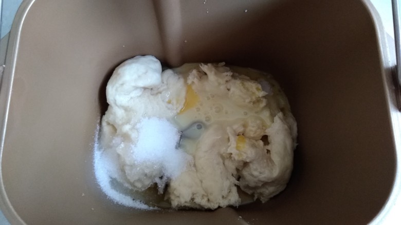 面包机版炼奶面包,将发酵好的中种撕成小块放入面包桶,倒入水、炼奶、蛋液、糖和盐