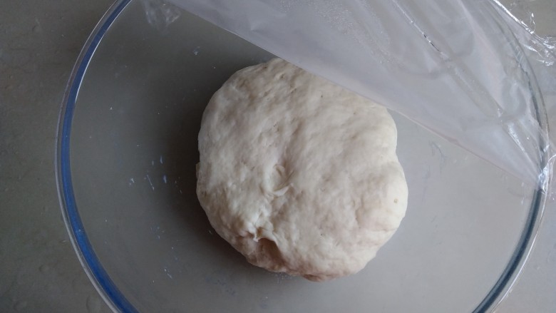 面包机版炼奶面包,先做中种,温牛奶溶解酵母,倒入210克面粉,和成面团即可,可以用手揉,也可以用面包机揉几分钟。盖上保鲜膜,在室温下发酵3倍大