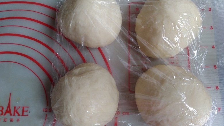 面包机版炼奶面包,将面团分成四等份滚圆,盖上保鲜膜松弛15分钟