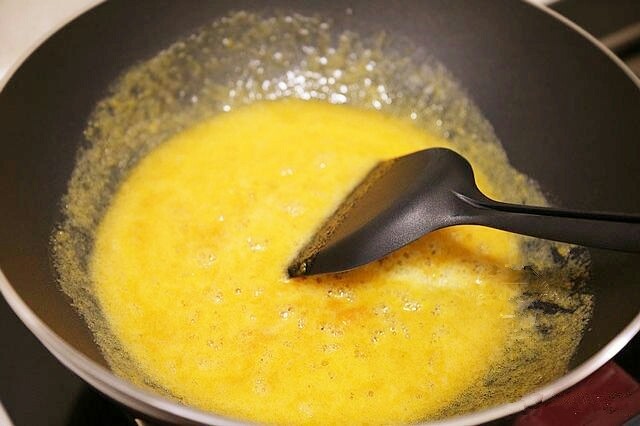 蟹黄豆腐,锅中下油,倒入捣好的蛋黄,小火翻炒,直到起小气泡。