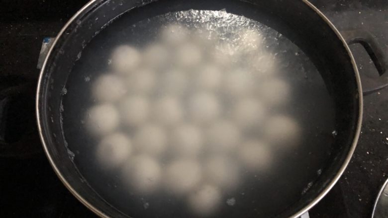 芝麻流心汤圆,锅里放水烧开后放入汤圆,用勺子背部轻轻滚动汤圆,防止粘锅。