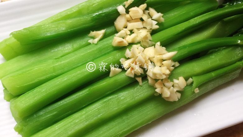 白灼芥蓝 快手经典菜,烫好的芥蓝捞出,滴干水分,摆放到盘中,然后把蒜末放上去。