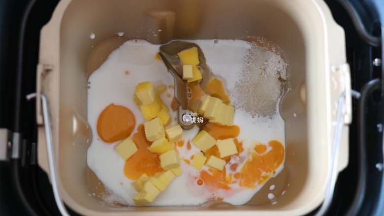 布里欧修面包,将全蛋液、牛奶倒入面包机的面包桶中,盐、糖对角放,放一半的黄油(30g);