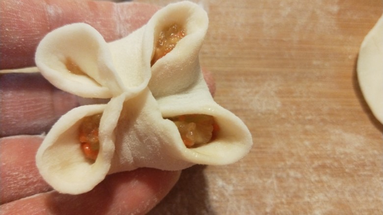 花样四喜蒸饺 新文美食,在对折捏紧,成为四角。