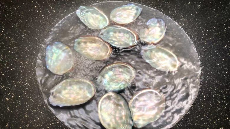 美味鲍鱼,锅里放入适量水,把洗干净的鲍鱼壳放入,开大火把水煮开,水开再煮3分钟,煮好把鲍鱼壳捞出来,摆入盘里待用。