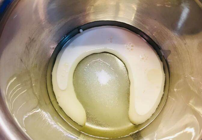 爆浆海盐红丝绒奶盖蛋糕,蛋糕体部分:牛奶,蛋黄用的糖,玉米油放入容器中,搅拌乳化。
