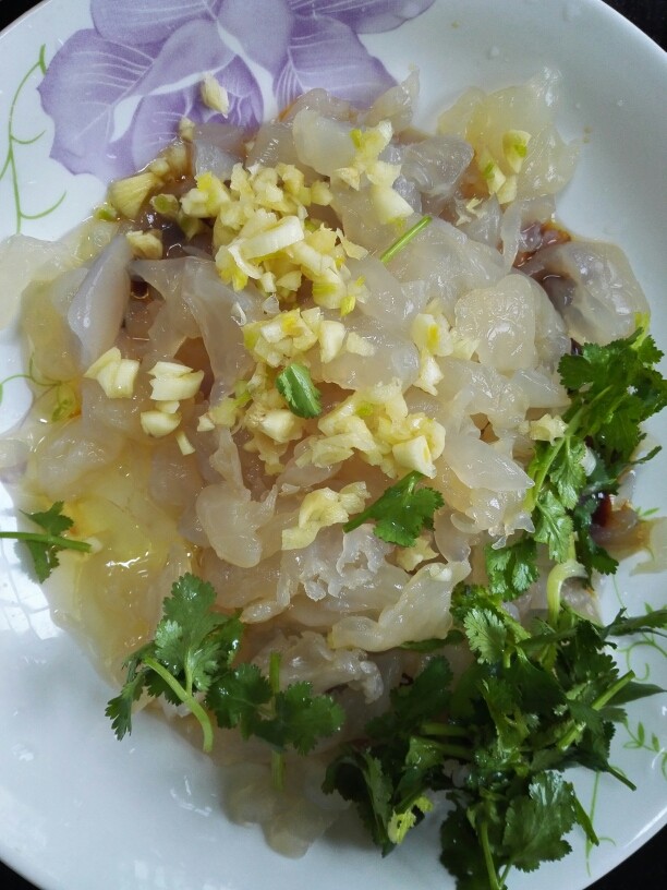酸辣海蜇丝,海蜇挤干净水分放入盘内,上面放上蒜末和香菜
