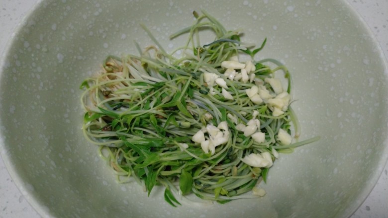 内豆腐拌绿豆芽,捞入碗中,加入蒜末。