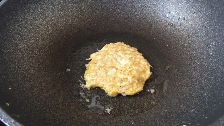 雪虾鸡蛋饼 (宝宝补钙佳品),旺火置锅,锅烧热,放入1小勺的食用油,用油把锅润一下,放入1大汤勺的雪虾鸡蛋液。