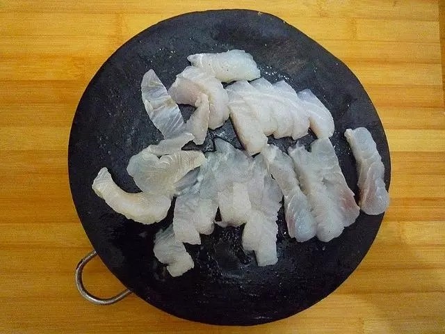 照烧龙利鱼,切好的龙利鱼放入容器中,加入少许食盐、白胡椒粉、1茶匙料酒抓匀腌渍几分钟。