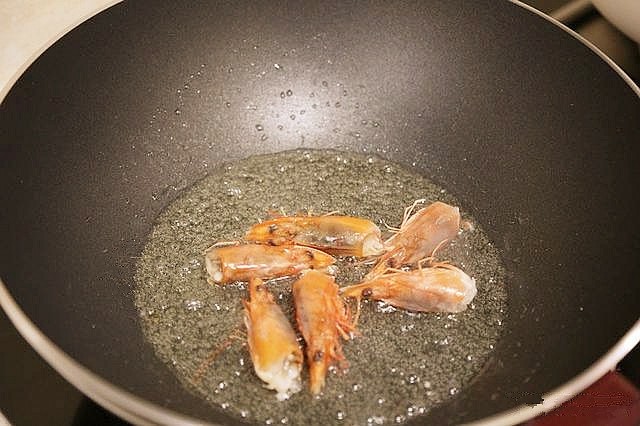 鲜虾粉丝煲,锅中倒入少许油,油热后,将虾头放入锅中煸炒出虾油,然后把虾头取出扔掉锅中留下虾油。