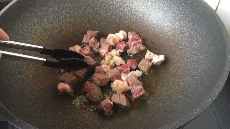 黑胡椒牛肉粒,将牛肉粒一面煎至变色,用夹子将牛肉粒反过来,煎另外一面,同样煎至变色。