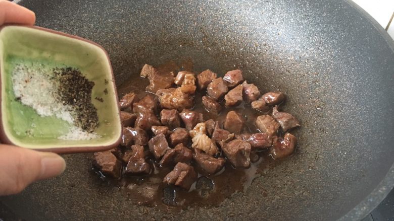 黑胡椒牛肉粒,用手撒入现磨黑胡椒碎和现磨海盐,翻炒均匀。 黑胡椒碎和盐的量依个人口味撒入。 撒黑胡椒碎时一定用手撒,且要撒的均匀些。