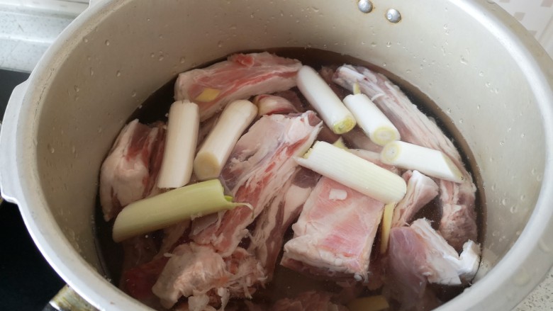 炖羊肉,捞出羊肉放入高压锅内,加水至没过羊肉一两厘米高,投入葱段姜片蒜