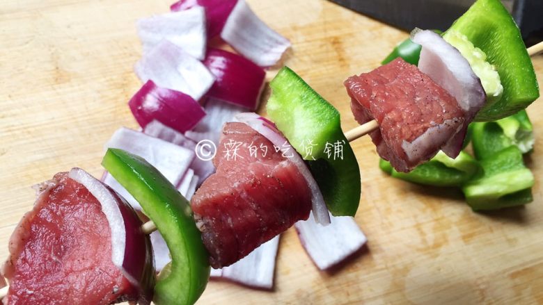 烤牛肉串,随后把腌好的牛肉、洋葱、青椒,串到竹签上。